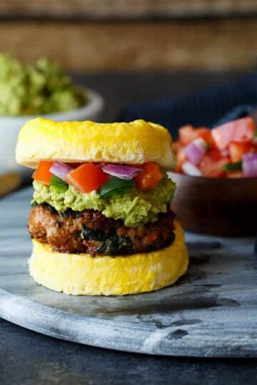 Paleo Southwest Sausage Egg Sandwiches. A healthy Mexican breakfast, using scrambled eggs in place of the bun! Topped with guacamole and pico de gallo, too!