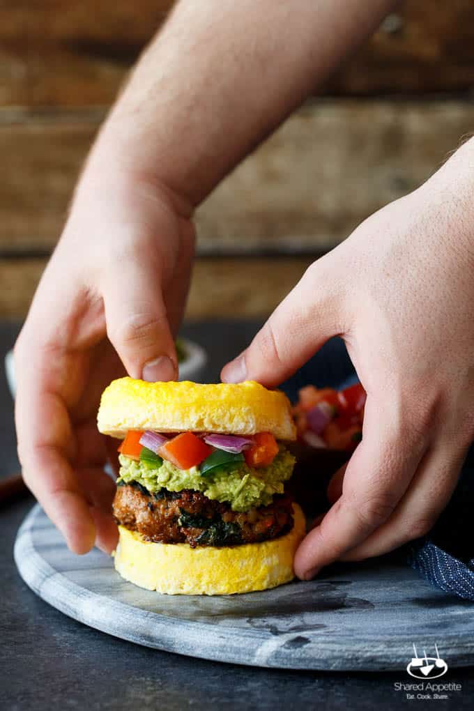 Paleo Southwest Sausage Egg Sandwiches. A healthy Mexican breakfast, using scrambled eggs in place of the bun! Topped with guacamole and pico de gallo, too! 