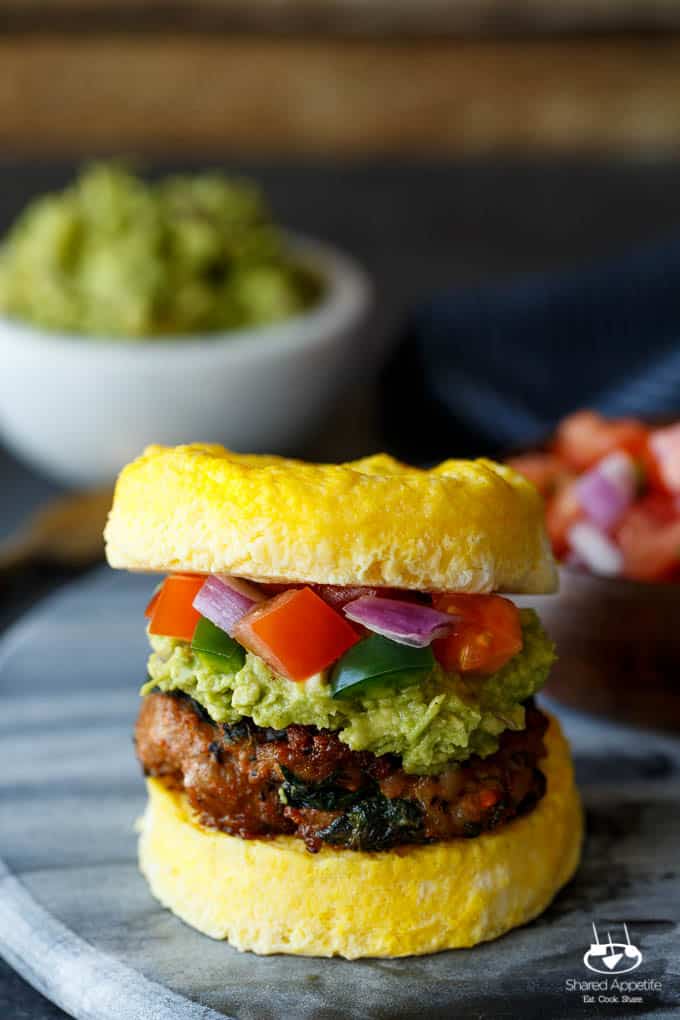 Paleo Southwest Sausage Egg Sandwiches. A healthy Mexican breakfast, using scrambled eggs in place of the bun! Topped with guacamole and pico de gallo, too! 