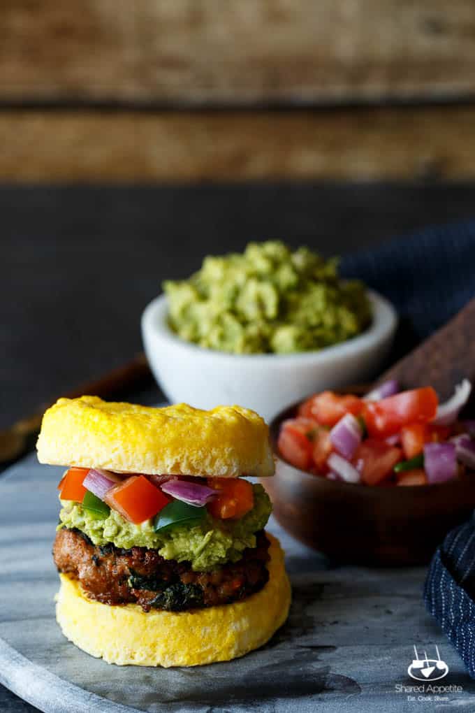 Paleo Southwest Sausage Egg Sandwiches. A healthy Mexican breakfast, using scrambled eggs in place of the bun! Topped with guacamole and pico de gallo, too! 