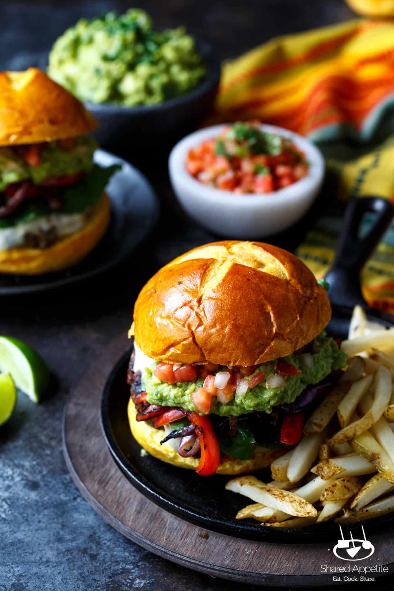 Fajita Burgers with grilled peppers and onions, guacamole, and pico de gallo | sharedappetite.com