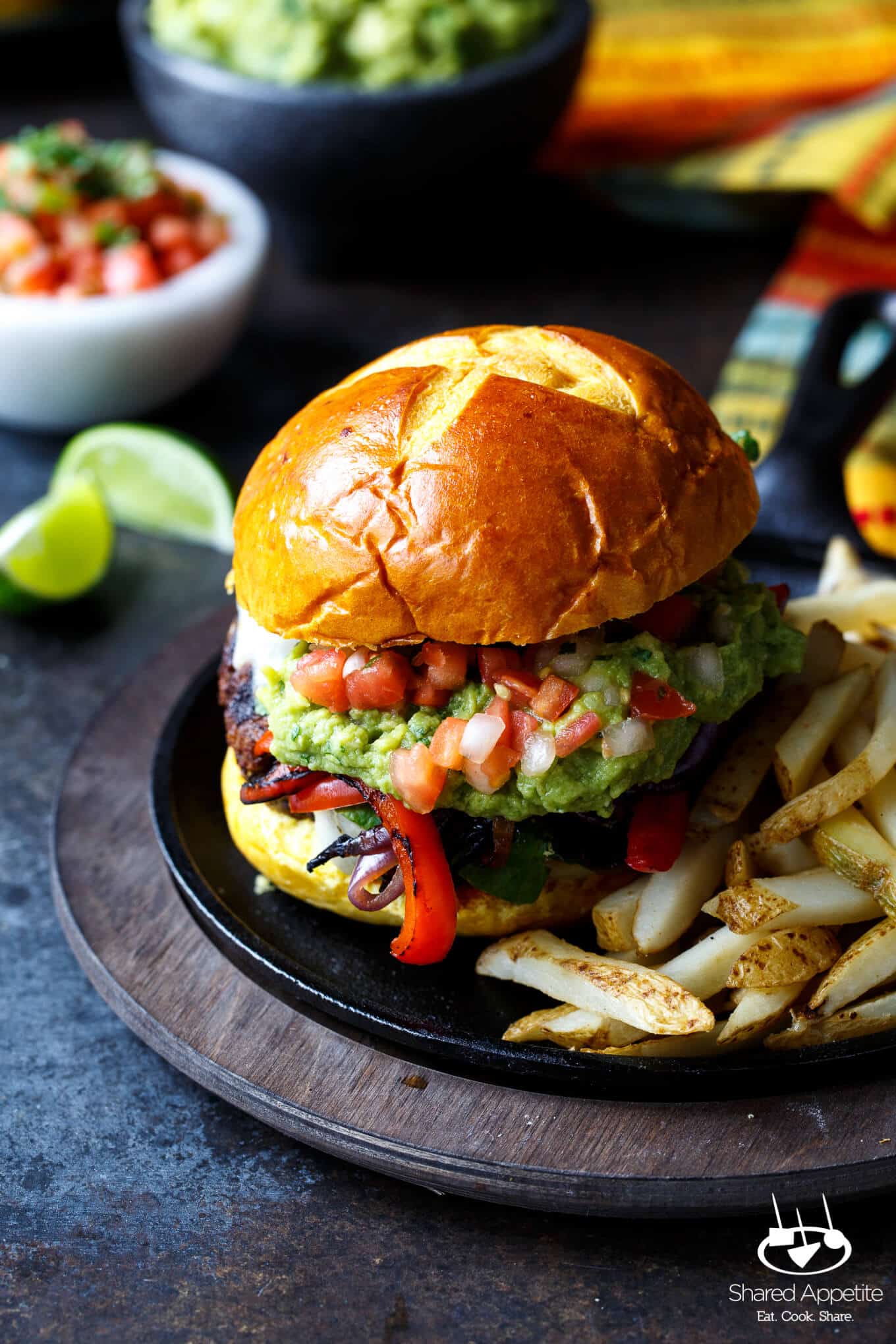 Fajita Burgers with grilled peppers and onions, guacamole, and pico de gallo | sharedappetite.com