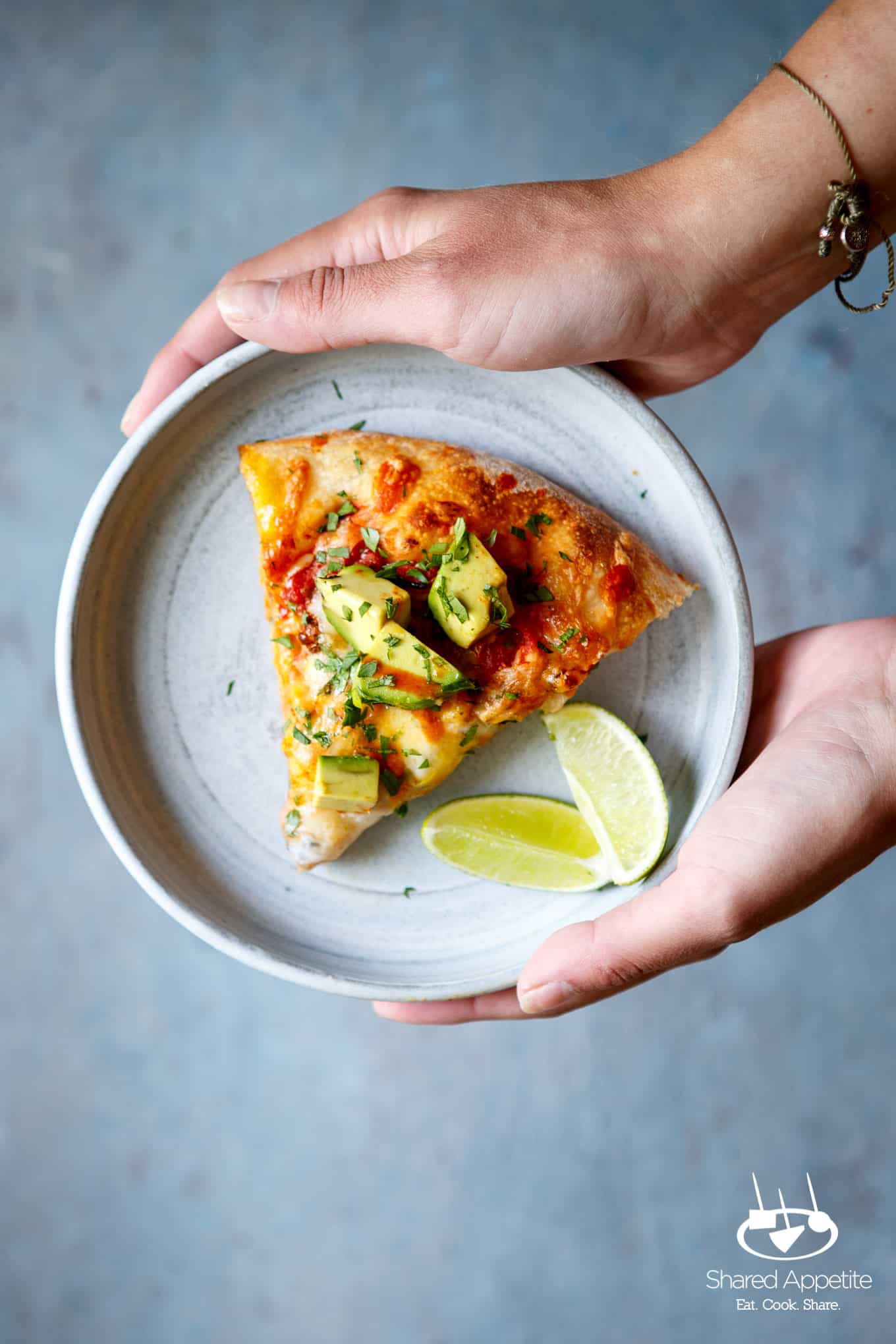 Holding a plate with a slice of Huevos Rancheros Pizza with Turkey Chorizo | sharedappetite.com