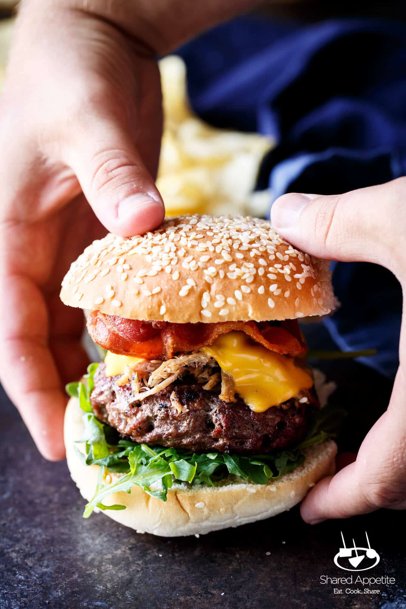 Grabbing with my hands the Pulled Pork Bacon Cheeseburgers | sharedappetite.com