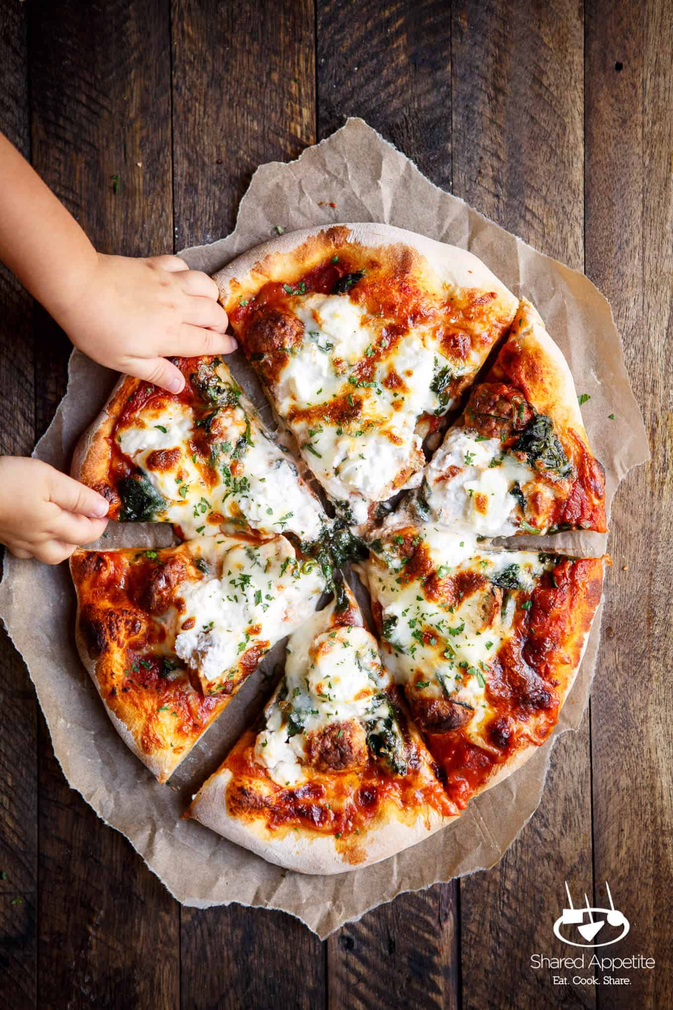 my daughter grabbing a slice of this Meatball, Spinach, and Ricotta Pizza