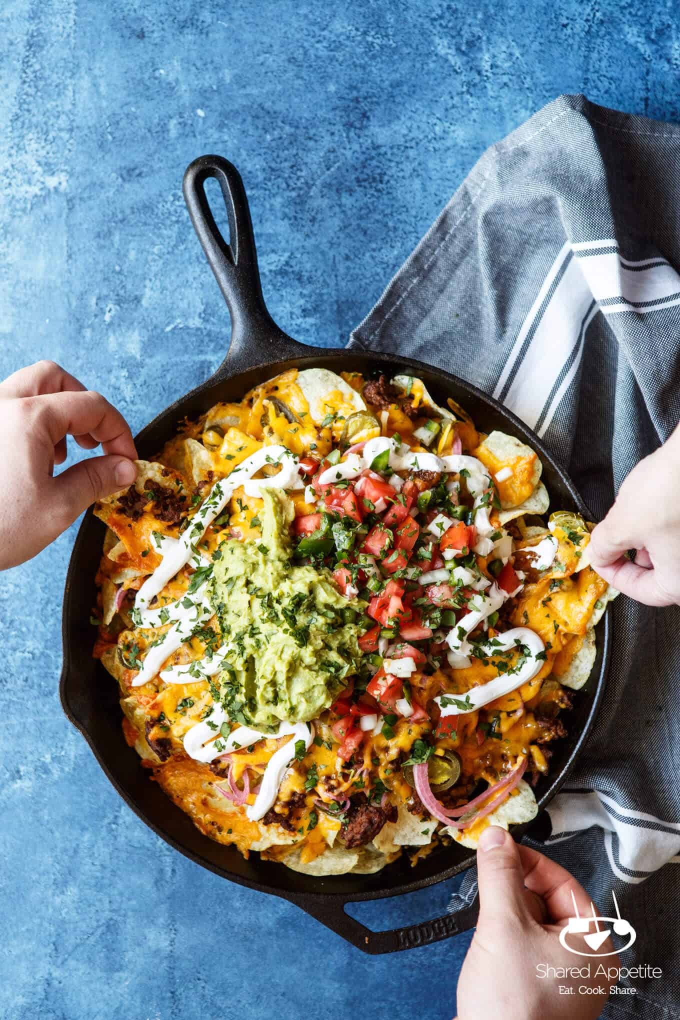 Everyone digging into these Skillet Loaded Taco Potato Chip Nachos | sharedappetite.com